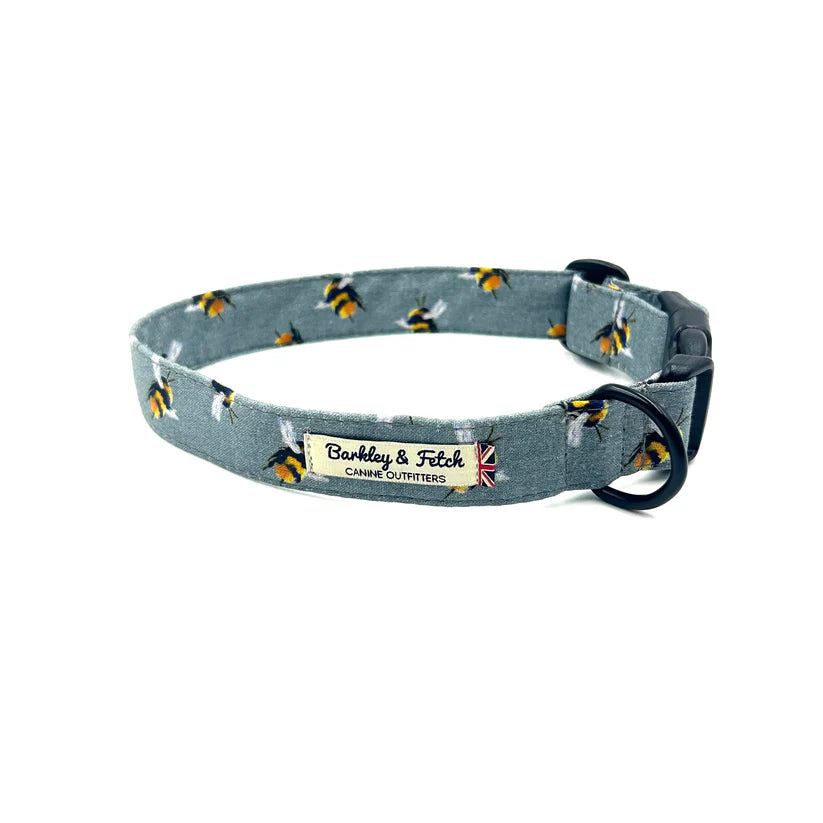 A grey dog collar with a bee print pattern, made by Barkley & Fetch, featuring a plastic side-release clip and a black powder-coated D-ring.