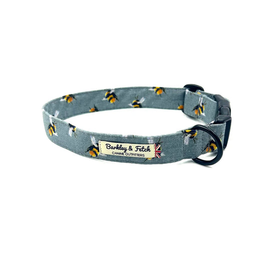 A grey dog collar with a bee print pattern, made by Barkley & Fetch, featuring a plastic side-release clip and a black powder-coated D-ring.