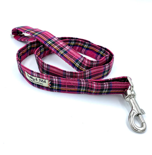 A bright pink tartan pattern dog lead with a comfortable loop handle, an accessory attachment ring, and a strong steel trigger clip.